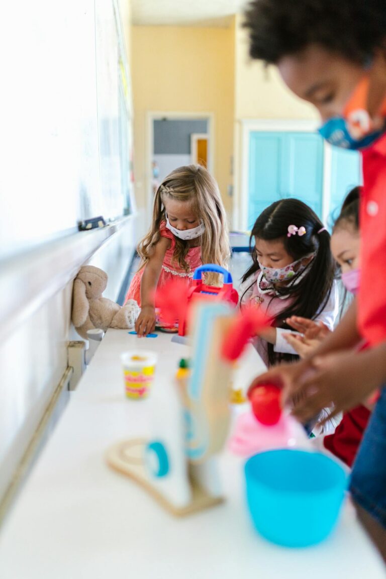 Kids engaged in creative play at school with masks on, promoting safe learning.
